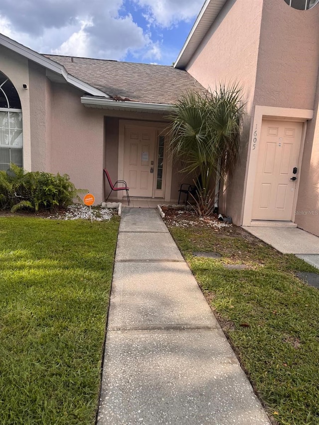 1603 Emily Ct, Kissimmee, FL 34744 - property entrance with stucco siding, a lawn, and roof with shingles