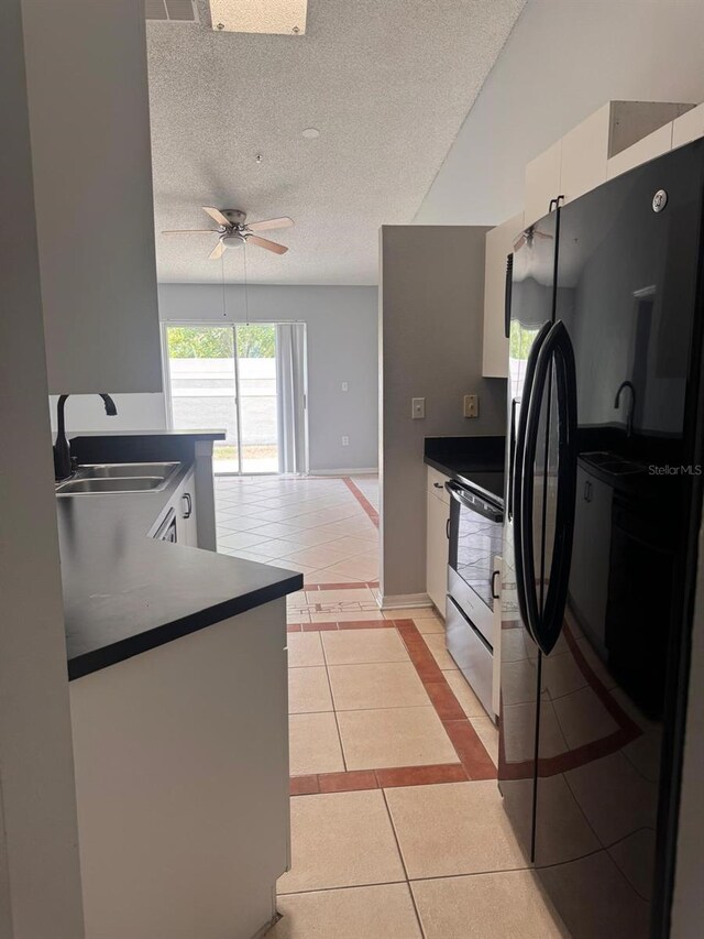 1603 Emily Ct, Kissimmee, FL 34744 - kitchen with electric stove, freestanding refrigerator, light tile patterned floors, dark countertops, and white cabinetry