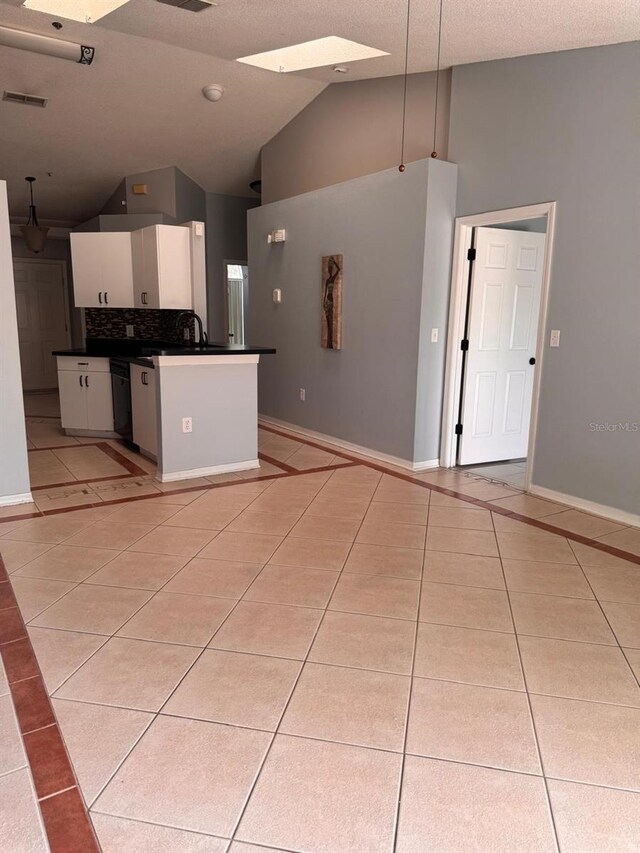 1603 Emily Ct, Kissimmee, FL 34744 - kitchen featuring light tile patterned floors, dark countertops, white cabinetry, high vaulted ceiling, and inlaid floor details