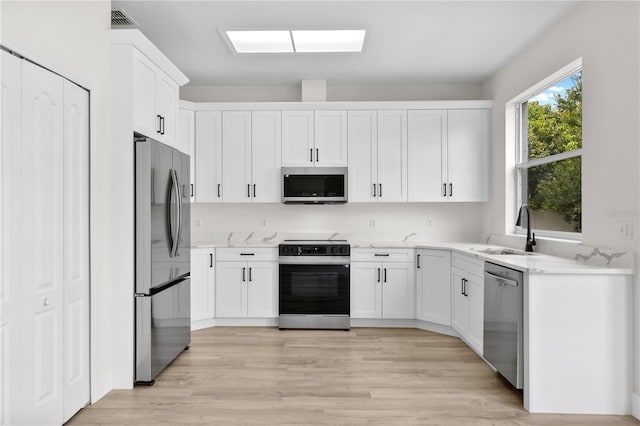 12917 Grovehurst Ave, Winter Garden, FL 34787 - kitchen with appliances with stainless steel finishes, a sink, white cabinetry, and light wood-style flooring