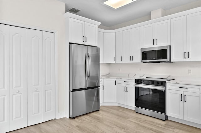 12917 Grovehurst Ave, Winter Garden, FL 34787 - kitchen with appliances with stainless steel finishes, white cabinets, light wood-style floors, and light stone countertops