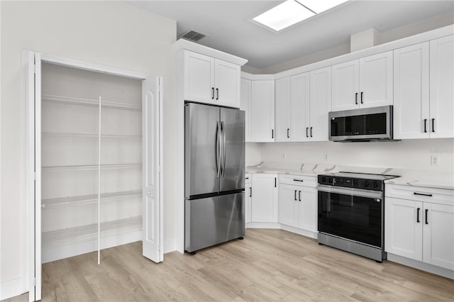 12917 Grovehurst Ave, Winter Garden, FL 34787 - kitchen with stainless steel appliances, light wood finished floors, white cabinets, and baseboards