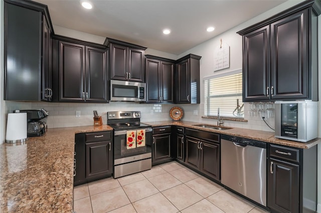 11631 Mystery Ln, Orlando, FL 32832 - kitchen featuring appliances with stainless steel finishes, a sink, backsplash, light tile patterned floors, and light stone counters