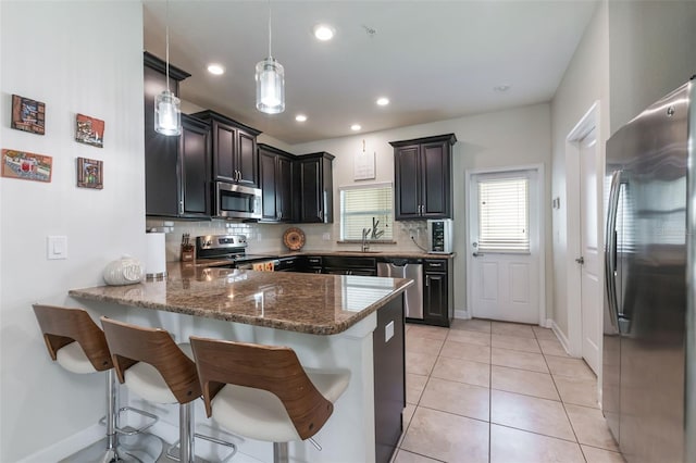 11631 Mystery Ln, Orlando, FL 32832 - kitchen with stainless steel appliances, a peninsula, a sink, backsplash, and dark stone counters