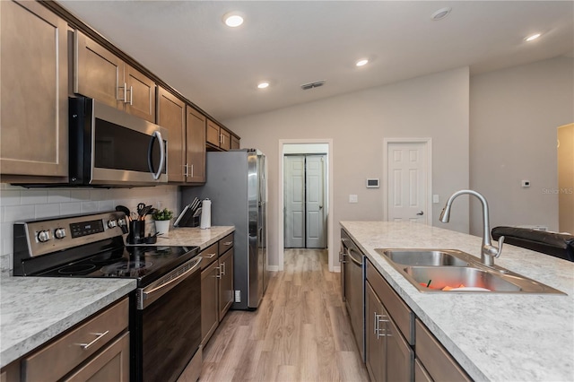 871 Orleans Dr, Eagle Lake, FL 33839 - kitchen with stainless steel appliances, a sink, light wood-style flooring, decorative backsplash, and lofted ceiling