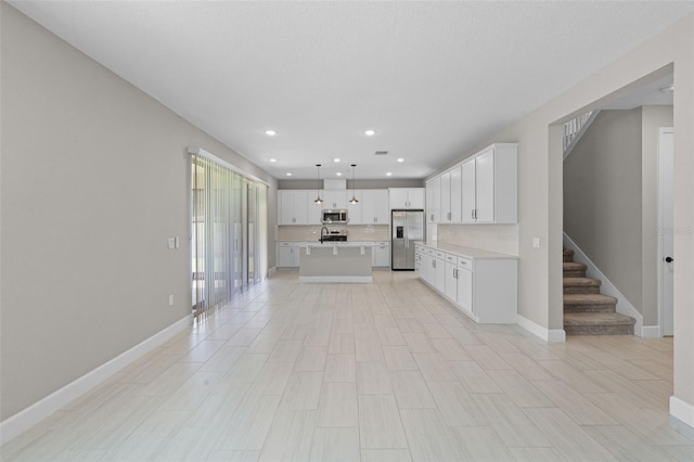 10249 Spring Lake Dr, Clermont, FL 34711 - kitchen featuring stainless steel appliances, light countertops, a center island with sink, white cabinets, and recessed lighting