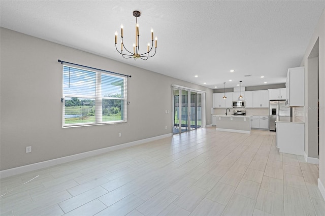 10249 Spring Lake Dr, Clermont, FL 34711 - unfurnished living room with a chandelier, plenty of natural light, recessed lighting, and a textured ceiling