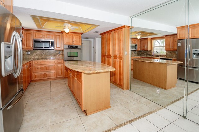 2 Pirates Cv, Ormond Beach, FL 32176 - kitchen featuring appliances with stainless steel finishes, a center island, a tray ceiling, a ceiling fan, and a sink