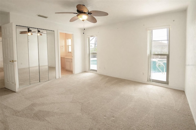 2 Pirates Cv, Ormond Beach, FL 32176 - unfurnished bedroom featuring light colored carpet, multiple windows, ensuite bath, and ceiling fan