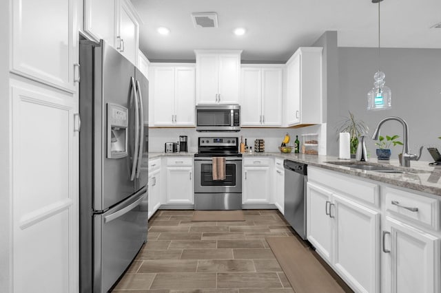 7573 Laureate Blvd Unit 1-404, Orlando, FL 32827 - kitchen with appliances with stainless steel finishes, a sink, white cabinetry, light stone counters, and recessed lighting