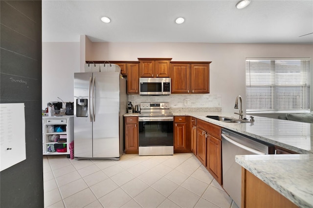 4558 Redmond Pl, Sanford, FL 32771 - kitchen with appliances with stainless steel finishes, a sink, brown cabinets, light stone countertops, and light tile patterned floors