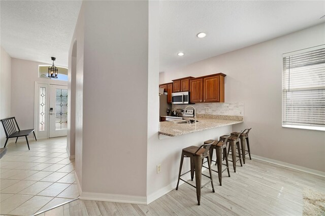 4558 Redmond Pl, Sanford, FL 32771 - kitchen with appliances with stainless steel finishes, a breakfast bar, plenty of natural light, brown cabinetry, and recessed lighting