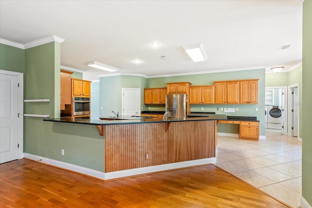 17631 Vista Belle Ct, Montverde, FL 34756 - kitchen featuring appliances with stainless steel finishes, crown molding, a breakfast bar, washer / clothes dryer, and a peninsula