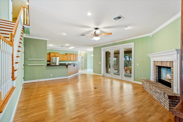 17631 Vista Belle Ct, Montverde, FL 34756 - unfurnished living room with crown molding, a ceiling fan, light wood-type flooring, a fireplace, and stairway