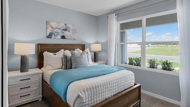 bedroom with dark colored carpet and baseboards