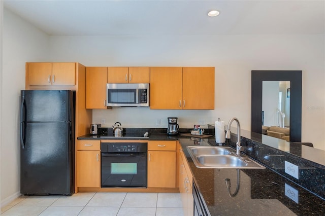kitchen featuring black appliances, a sink, dark stone countertops, light tile patterned flooring, and brown cabinets