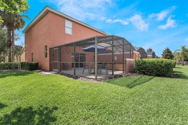 back of house with a patio area, stucco siding, a yard, and glass enclosure