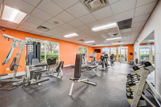 workout area with a paneled ceiling and baseboards