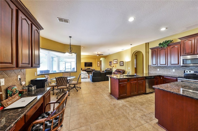 2921 Falconhill Dr, Apopka, FL 32712 - kitchen featuring stainless steel appliances, a sink, arched walkways, a peninsula, and backsplash