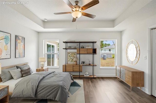 13881 SW 80th Ave, Ocala, FL 34473 - bedroom with a tray ceiling, multiple windows, wood finished floors, and baseboards