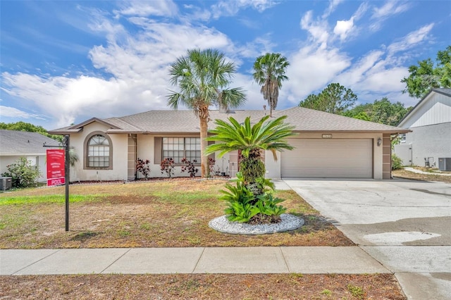 ranch-style home featuring stucco siding, a garage, driveway, and central AC unit