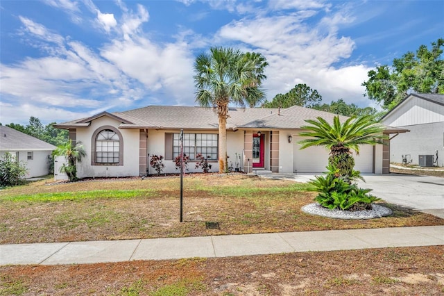 ranch-style home with a garage, central air condition unit, driveway, stucco siding, and roof with shingles