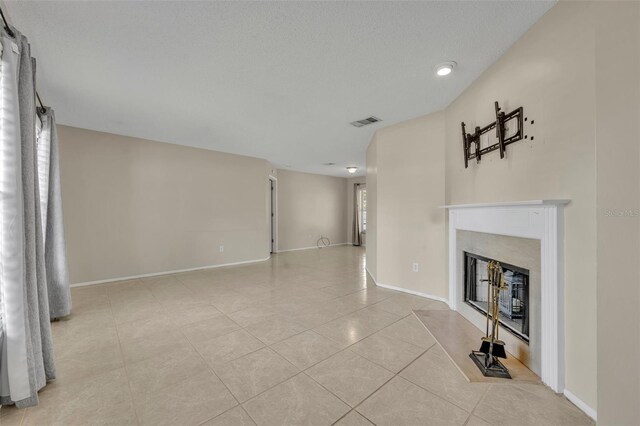 unfurnished living room with tile patterned flooring, a glass covered fireplace, and baseboards