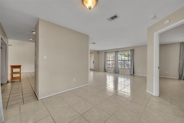 empty room featuring light tile patterned flooring, baseboards, a textured ceiling, and a smoke detector