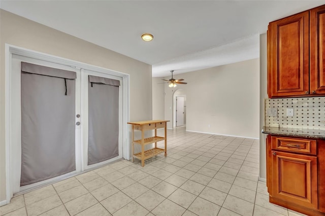 kitchen with ceiling fan, backsplash, stone counters, light tile patterned flooring, and baseboards