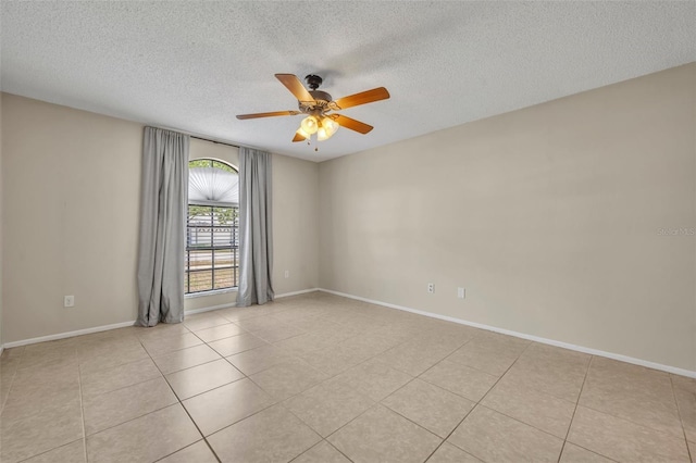 unfurnished room featuring ceiling fan, light tile patterned floors, a textured ceiling, and baseboards