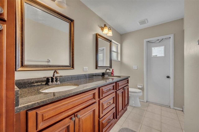 bathroom featuring tile patterned floors, toilet, double vanity, and baseboards