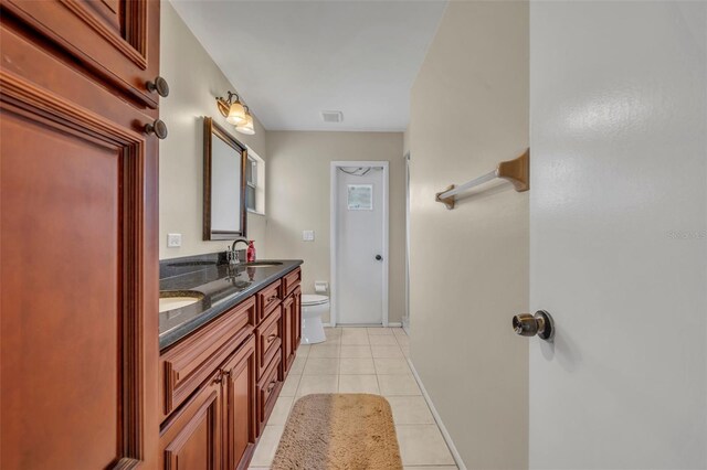 bathroom with toilet, tile patterned flooring, double vanity, and baseboards