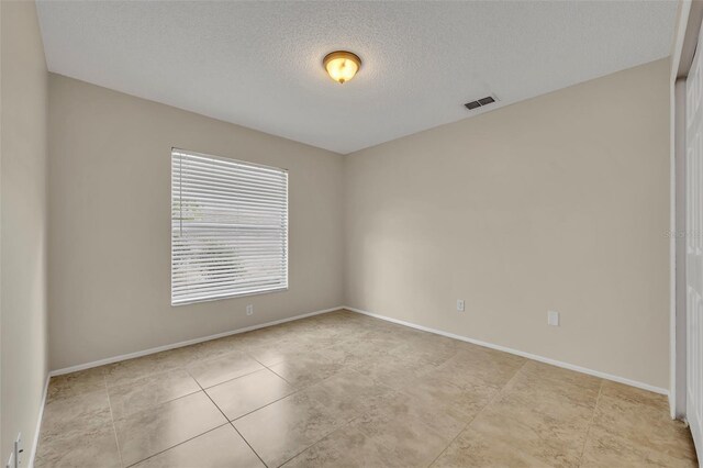 unfurnished room with a textured ceiling, baseboards, and light tile patterned floors