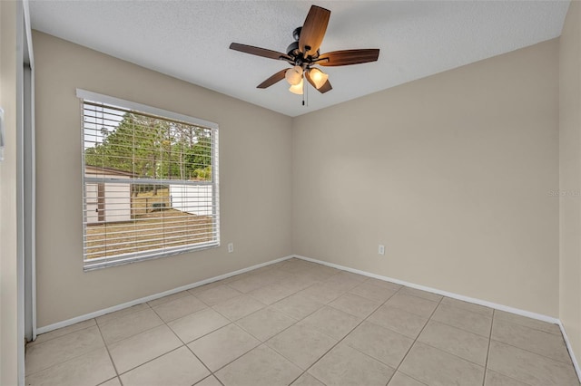 unfurnished room featuring a ceiling fan, baseboards, light tile patterned floors, and a textured ceiling