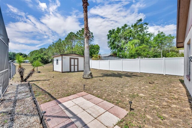 fenced backyard featuring a shed, a patio area, and an outbuilding