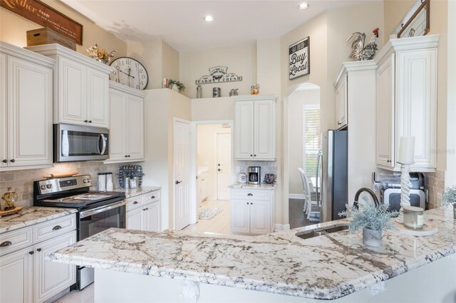 441 Hightower Dr, Debary, FL 32713 - kitchen featuring appliances with stainless steel finishes, tasteful backsplash, arched walkways, a sink, and light stone counters