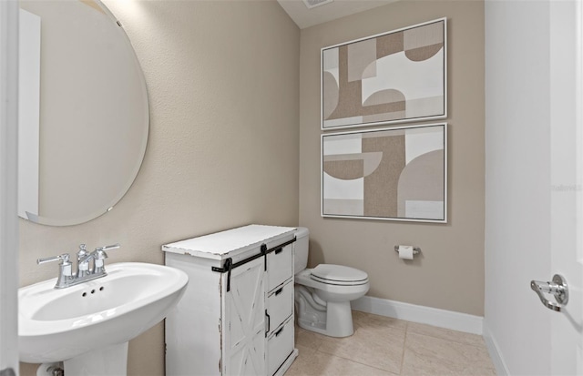 bathroom with a sink, tile patterned flooring, toilet, and baseboards