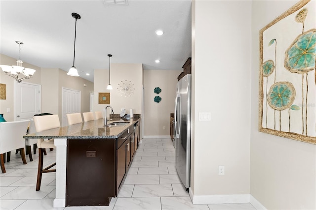 1596 Moon Valley Dr, Davenport, FL 33896 - kitchen featuring a kitchen bar, light marble finish flooring, freestanding refrigerator, dark brown cabinets, and recessed lighting