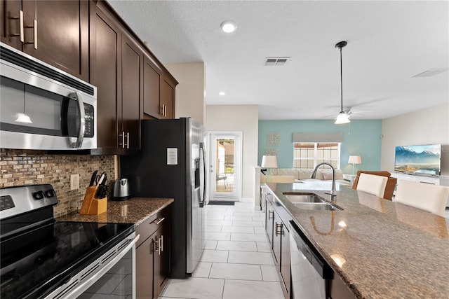 1596 Moon Valley Dr, Davenport, FL 33896 - kitchen with appliances with stainless steel finishes, a sink, tasteful backsplash, dark stone countertops, and dark brown cabinets