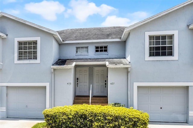 425 Eagle Ridge Dr Unit 425, Davenport, FL 33837 - property entrance featuring an attached garage, stucco siding, and roof with shingles