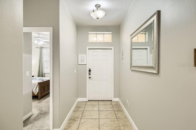 doorway featuring light tile patterned flooring, baseboards, and a textured ceiling