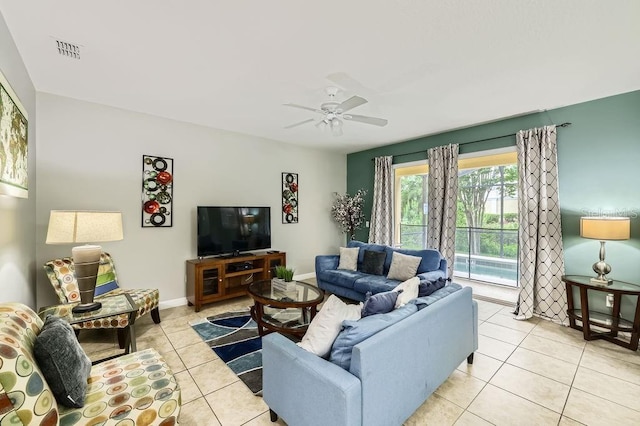 living area with light tile patterned floors, a ceiling fan, and baseboards