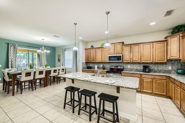 kitchen with appliances with stainless steel finishes, a sink, decorative backsplash, light tile patterned floors, and brown cabinets