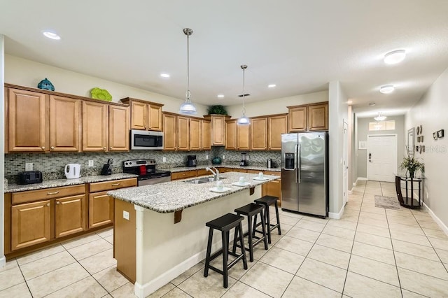 kitchen with stainless steel appliances, a sink, light tile patterned floors, brown cabinets, and recessed lighting