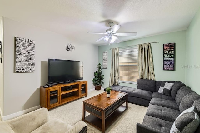 living area with ceiling fan, baseboards, light colored carpet, and a textured ceiling