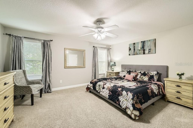 bedroom with light carpet, baseboards, a ceiling fan, and a textured ceiling