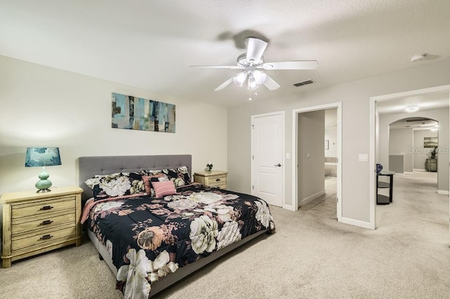 bedroom with light carpet, arched walkways, baseboards, and ceiling fan