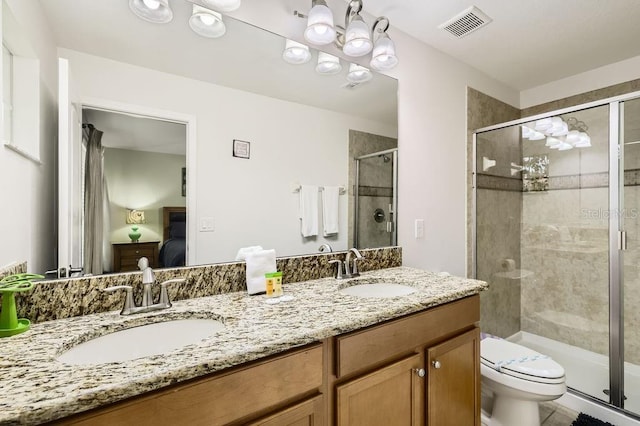 ensuite bathroom featuring toilet, double vanity, and a stall shower