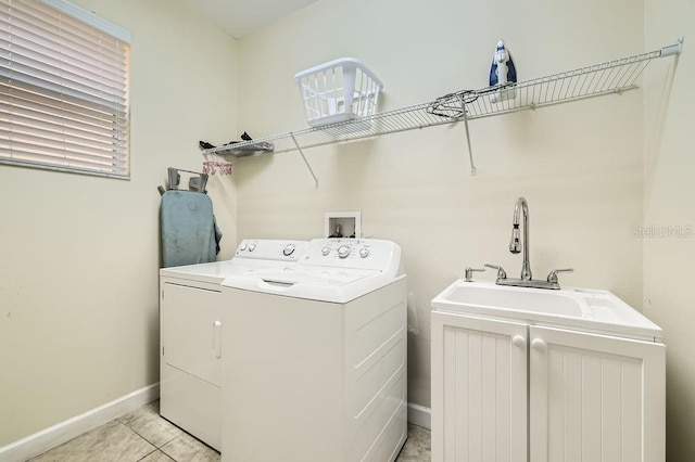 clothes washing area featuring baseboards, washing machine and clothes dryer, and light tile patterned floors