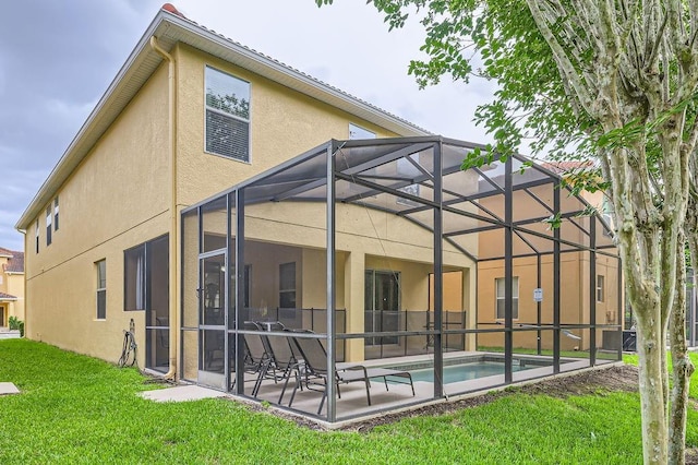 back of house featuring stucco siding, a patio area, a lanai, a lawn, and an outdoor pool
